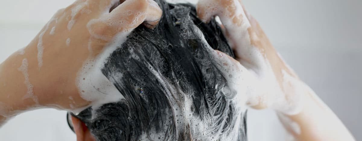 mujer lavando su cabello con champú