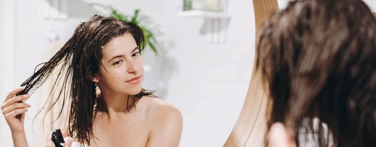 imagen de mujer observando su cabello en el espejo