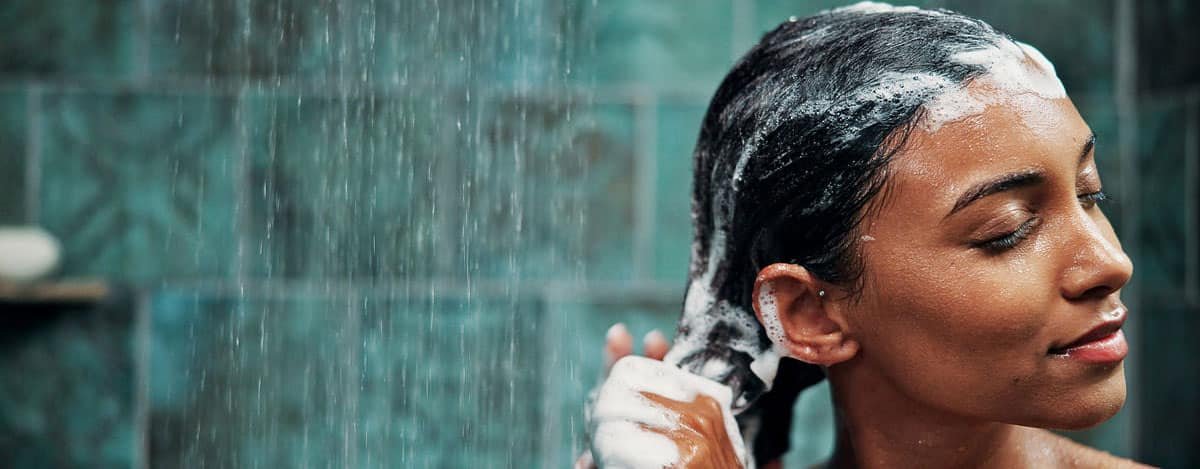 imagen de mujer lavándose el pelo con un champú muy espumoso