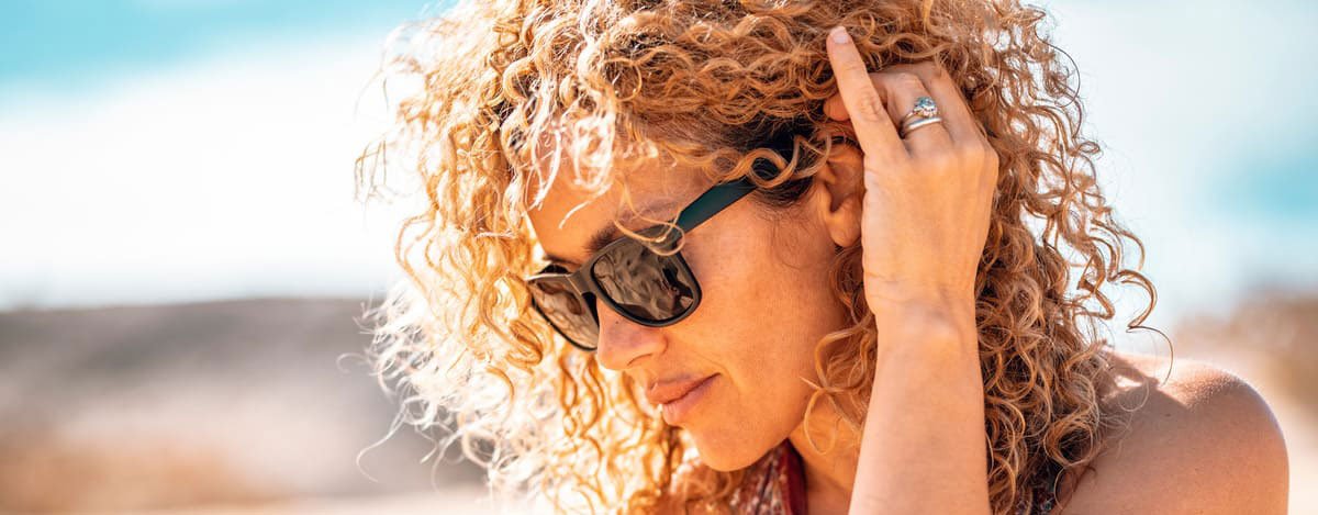 imagen de mujer con gafas de sol y perlo rizado