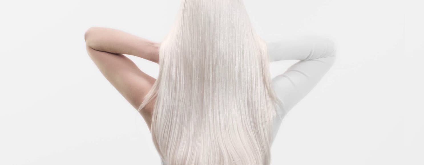 Mujer con cabello blanco largo, que muestra métodos anti-rotura adecuados para un cabello más sano y de aspecto más fuerte.