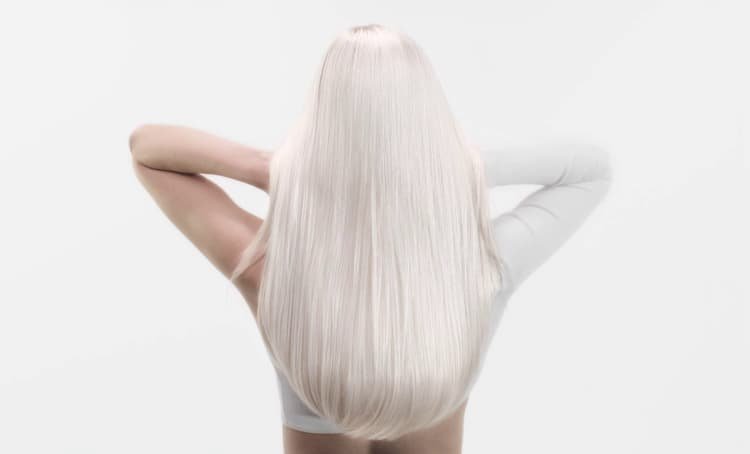 Mujer con cabello blanco largo, que muestra métodos anti-rotura adecuados para un cabello más sano y de aspecto más fuerte.