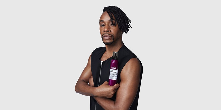 La imagen muestra a un hombre con cabello rizado peinado, sosteniendo el sérum Curl Expression, ilustrando la rutina de cuidado capilar para hombres con cabello rizado de L’Oréal.