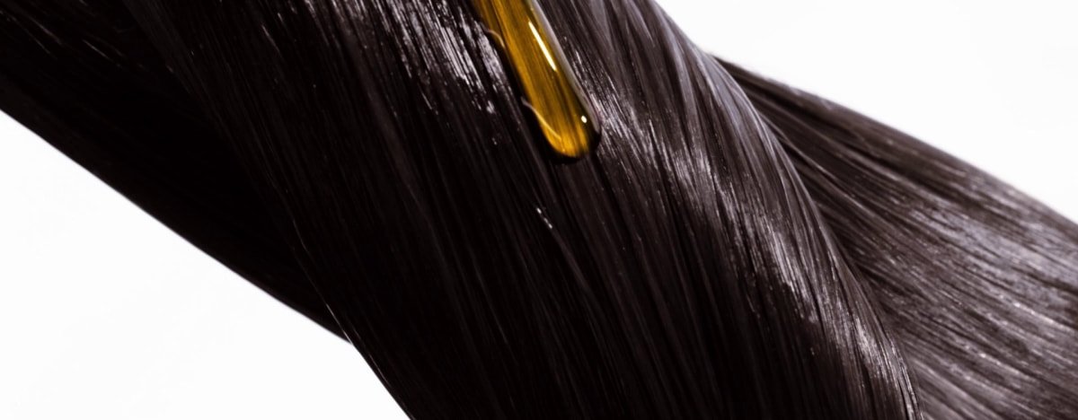 Aplicación paso a paso de aceite capilar para reparar el cabello seco y dañado, mostrando cómo se calienta una pequeña cantidad en las manos y luego se aplica uniformemente de medios a puntas.