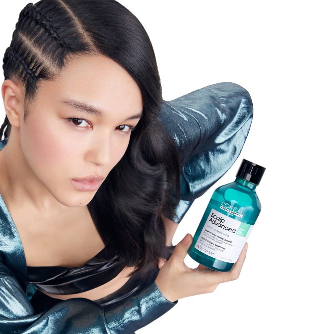 Mujer sosteniendo un frasco de champú L’Oréal Scalp Advanced, presentando la gama diseñada para eliminar el cabello graso.