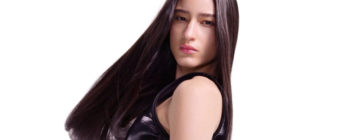 Tratamiento de queratina en curso en el cabello de una mujer, transformando la textura encrespada en una melena suave, lisa, fluida y brillante.