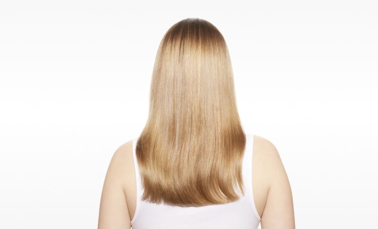 Mujer con el cabello visiblemente reparado, mostrando mayor fuerza, suavidad y brillo tras seguir la guía definitiva para reparar el cabello dañado.