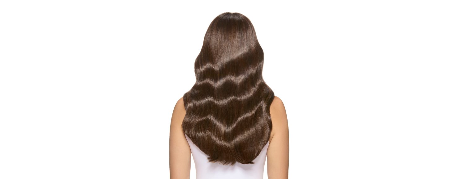 Mujer de pie sobre un fondo intergaláctico desértico, mostrando su vibrante color de cabello Bronce Titán y su audaz identidad.