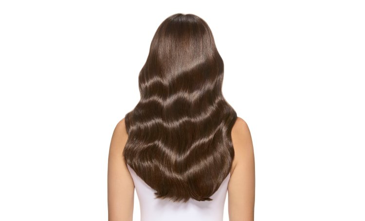Mujer de pie sobre un fondo intergaláctico desértico, mostrando su vibrante color de cabello Bronce Titán y su audaz identidad.