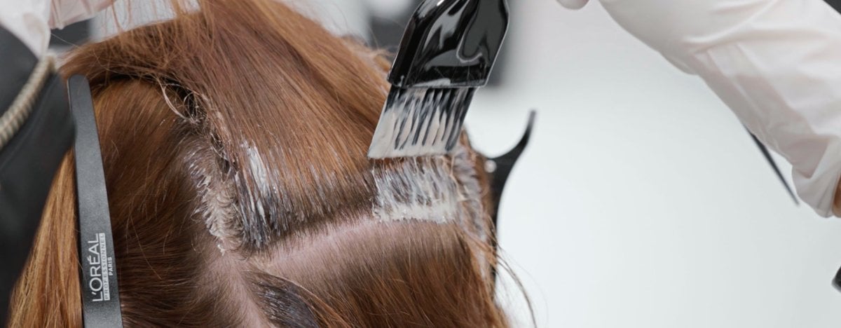 La imagen muestra a una mujer en la peluquería a la que le están tiñendo el pelo profesionalmente con el moderno color castaño espresso.