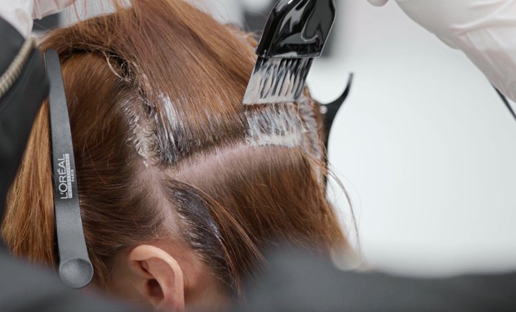 La imagen muestra a una mujer en la peluquería a la que le están tiñendo el pelo profesionalmente con el moderno color castaño espresso.