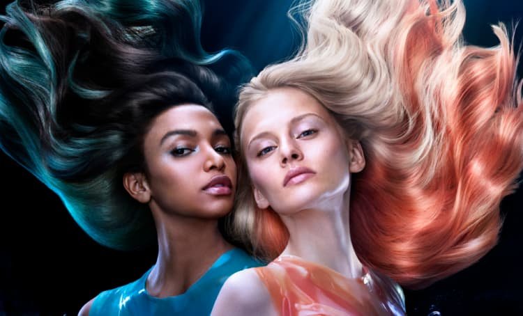 Dos mujeres posando, una con cabello rubio y mechones naranjas, la otra con cabello oscuro y reflejos azules intensos.