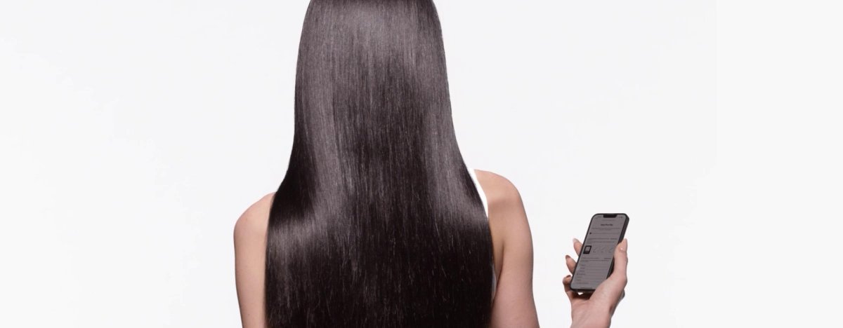 Mujer con cabello castaño largo y brillante que utiliza un diagnóstico capilar en línea para elegir sabiamente los productos más adecuados para su rutina de cuidado capilar.