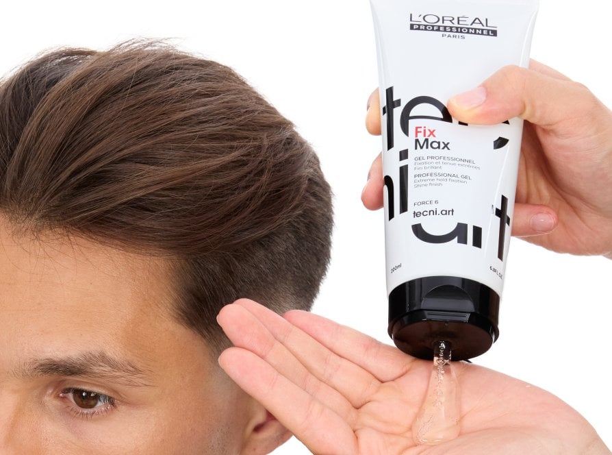 El foco se centra en el cabello de un hombre al que un estilista profesional está peinando con gel fijador, siguiendo la última tendencia en peinados.